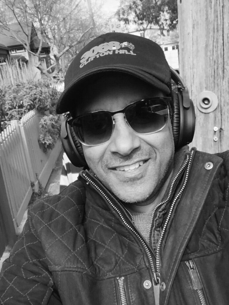 Sarath is pictured outside wearing his DJ headphones and a zip-up jacket. He is happy in this selfie.