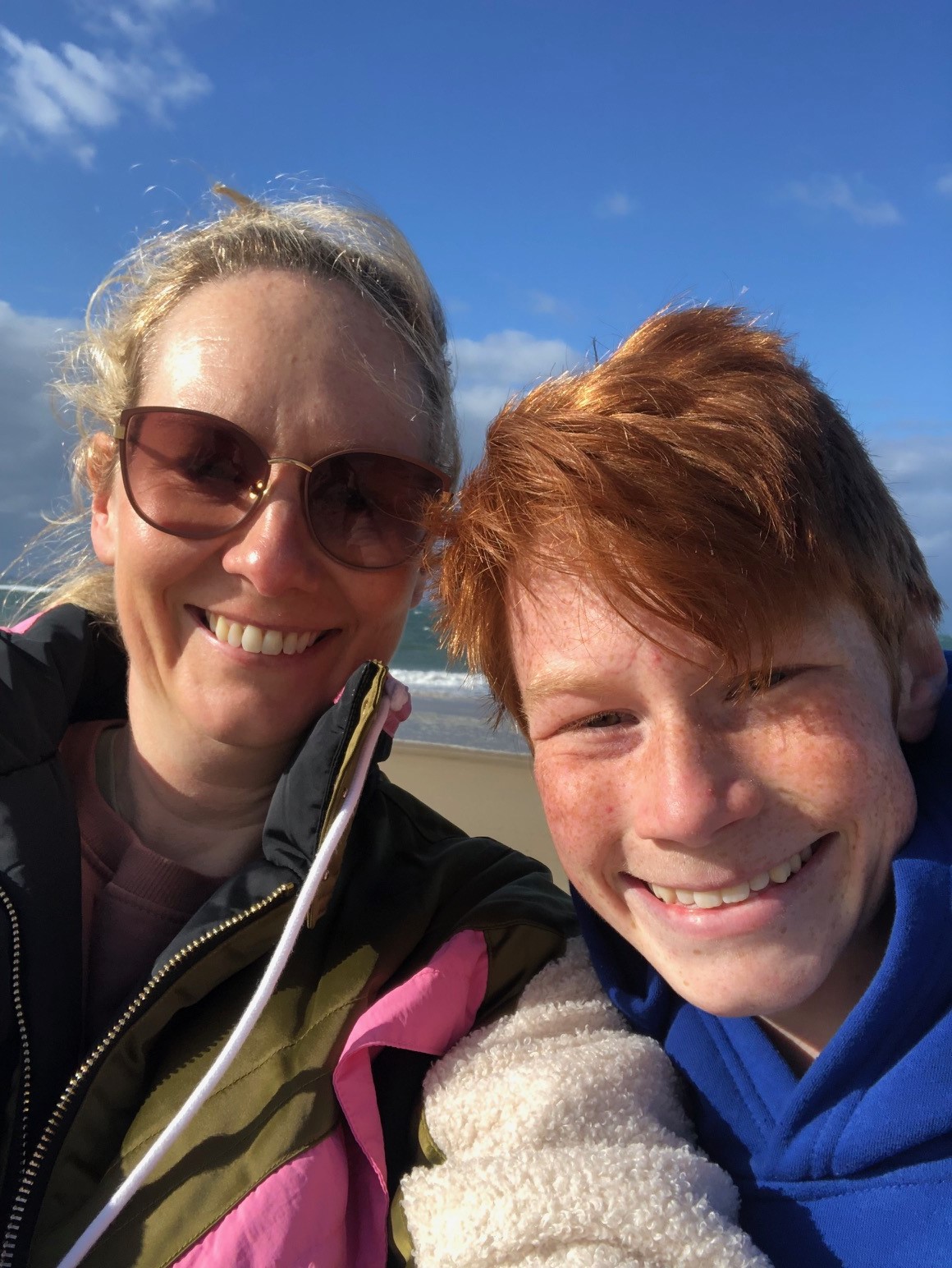 Elise and her son smile at the camera in front of an ocean view