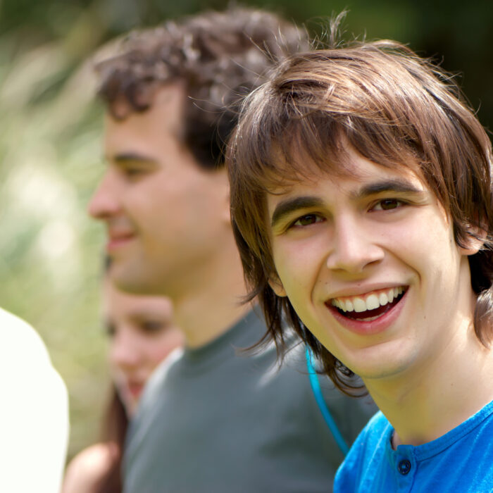 Photo of a teenage boy wearing a blue tshirt and smiling at the camera.