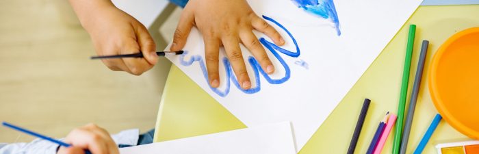 A photo of the hands of two small children finger painting.